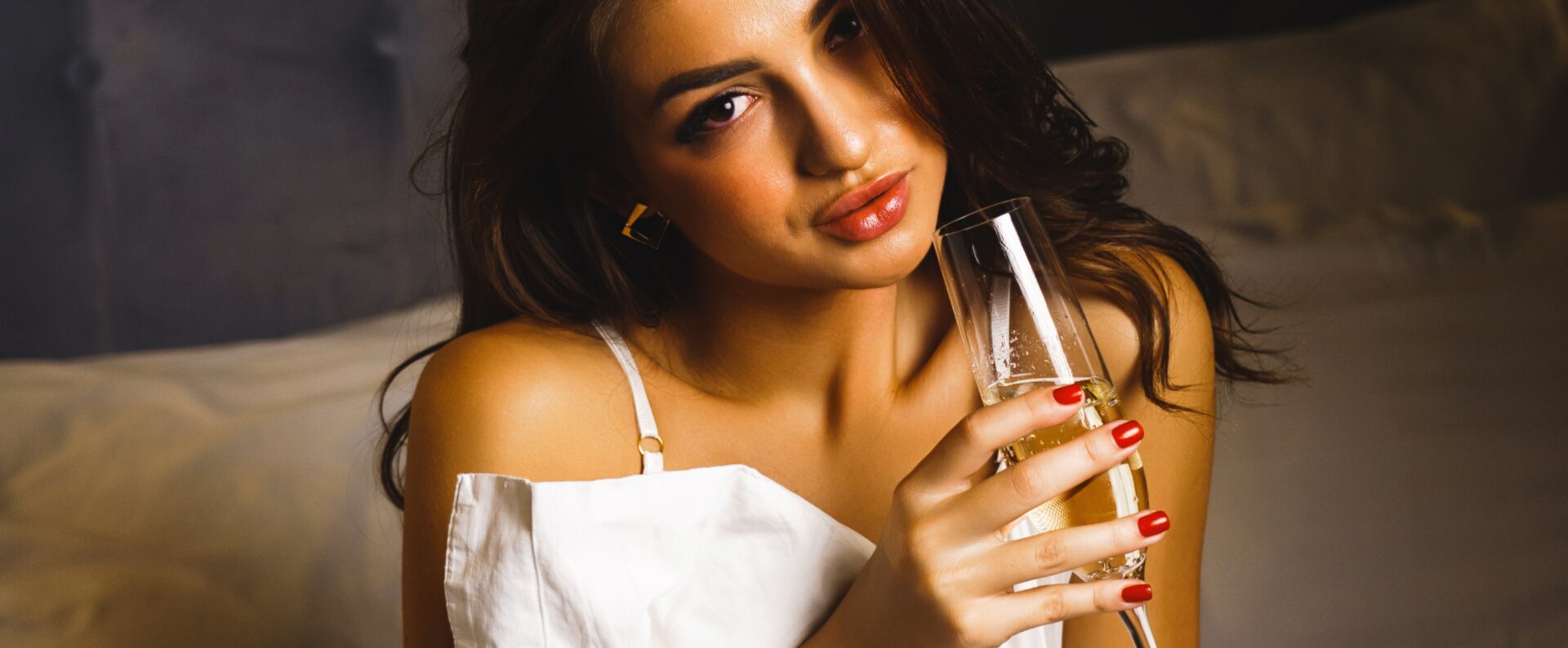 Sexy Woman Posing With A Glass Of Champagne In Bed Hintergrundbild des Headers